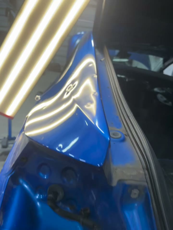 Blue fender with hail dents showing in reflected light