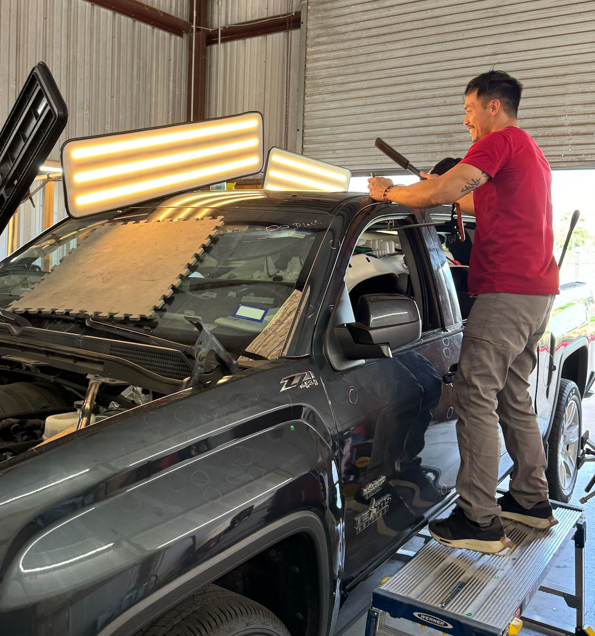 Hail Dent Pro technician working a truck roof under PDR lights