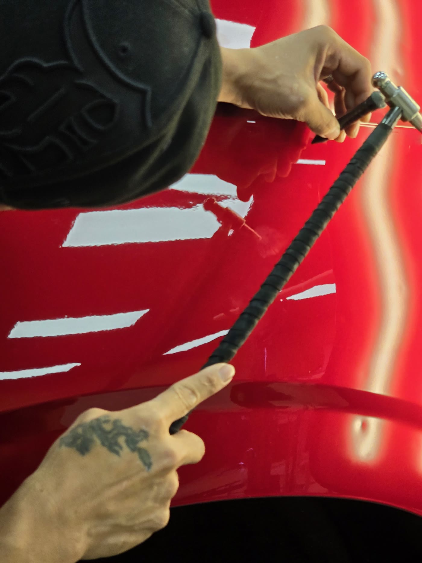 PDR tool working a dent on a red hood